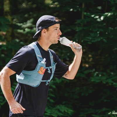 Man running outdoors with a water bottle in a forest setting