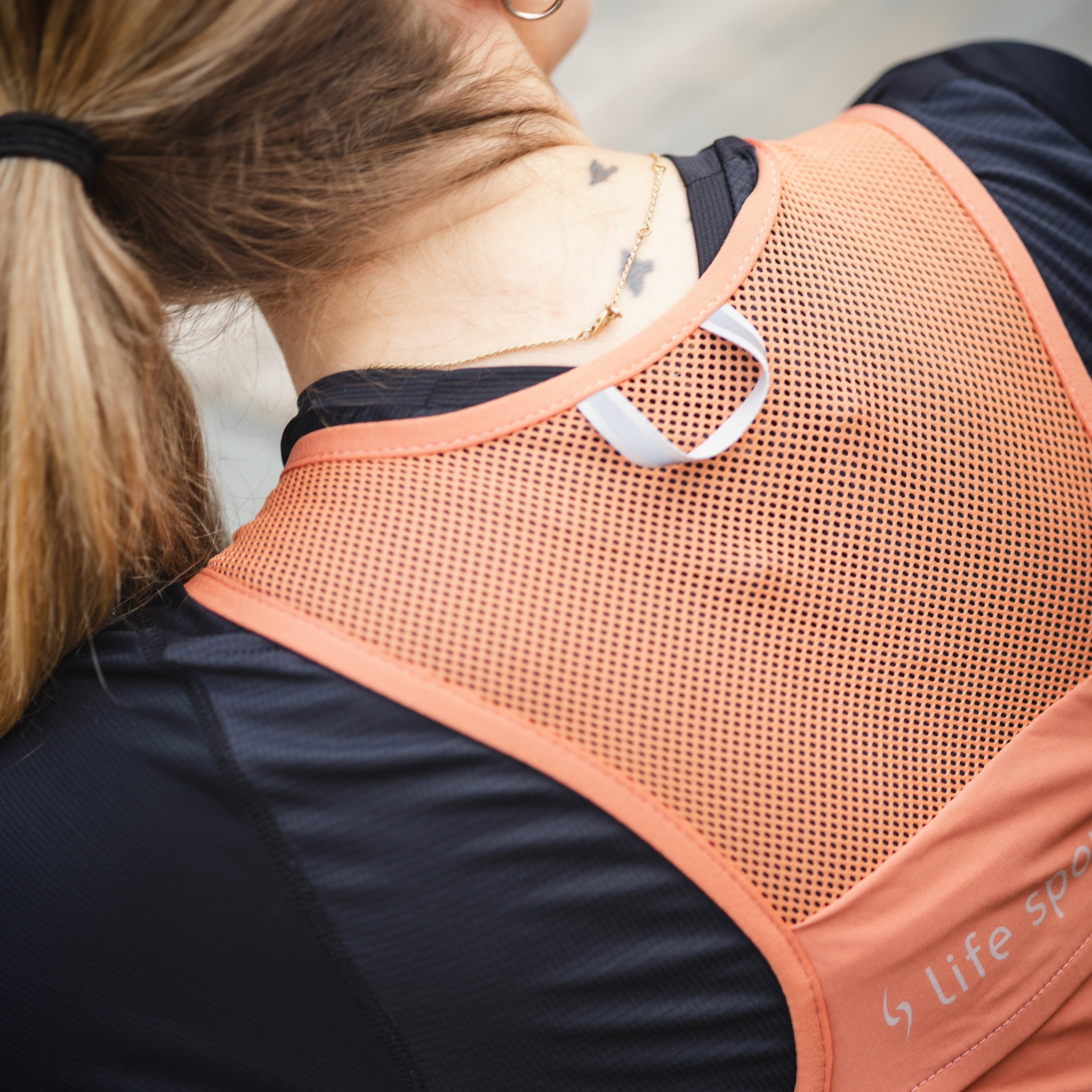 Person wearing an orange back support brace with 'Life Specific' branding. #color_terra-cota