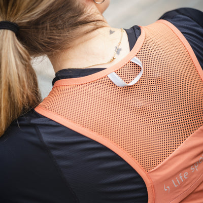 Person wearing an orange back support brace with 'Life Specific' branding. #color_terra-cota