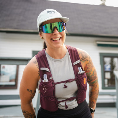 Person wearing a maroon running vest and sunglasses with a building in the background  #color_plume