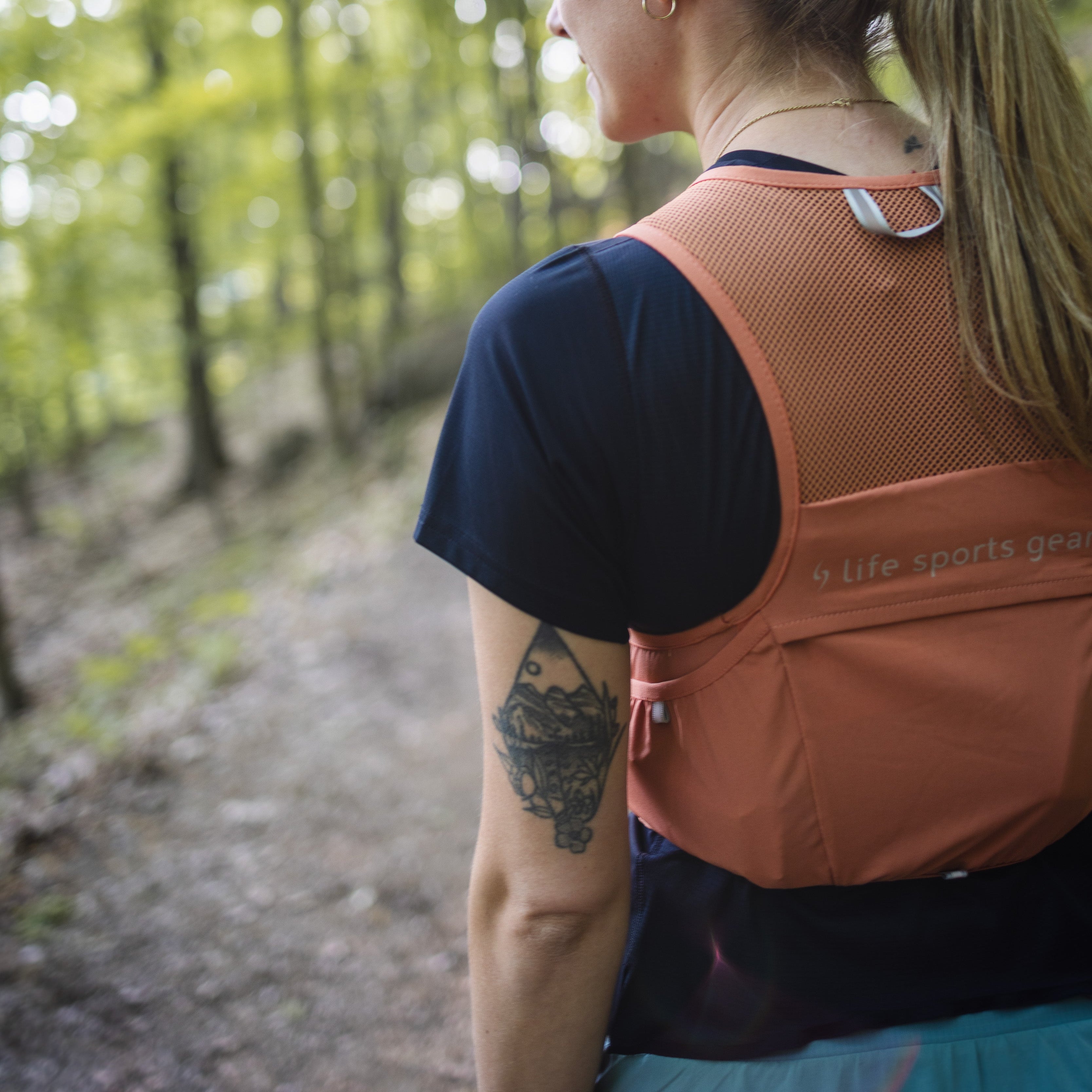 Person with an orange backpack walking on a forest path #color_terra-cota