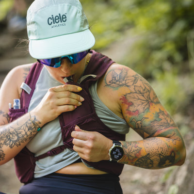 Person with tattoos outdoors, wearing a 'Ciele' cap and athletic gear. #color_plume