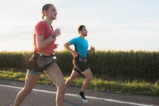 Homme et femme courant sur une route de campagne et portant une ceinture d'hydratation.