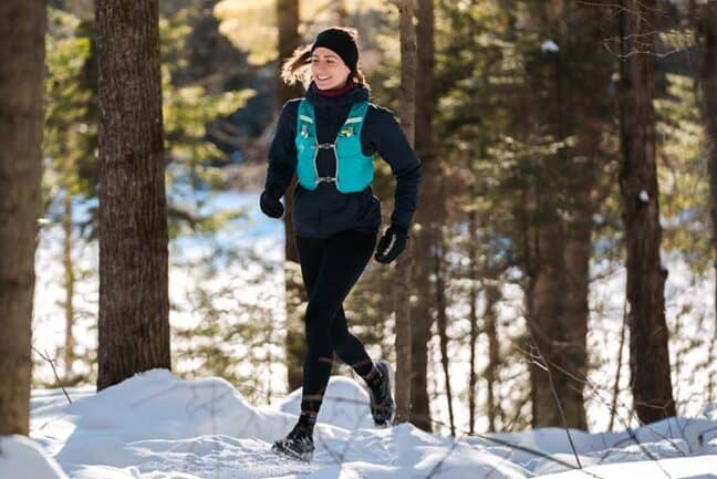 Coureuse en action sur un sentier enneigé pendant un entraînement d'hiver.