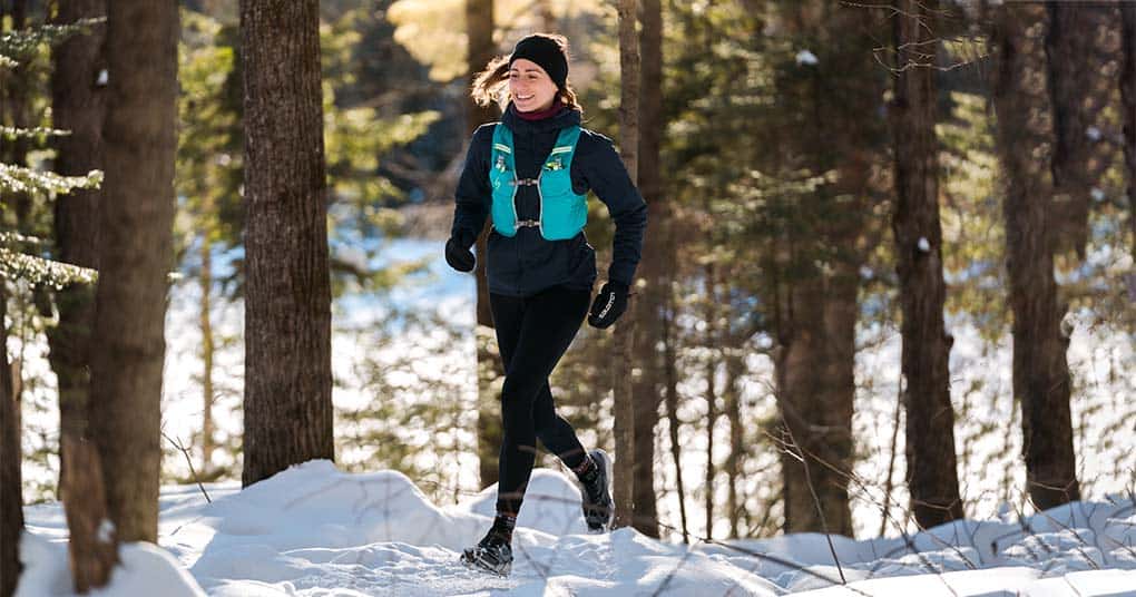 Coureuse en action sur un sentier enneigé pendant un entraînement d'hiver.