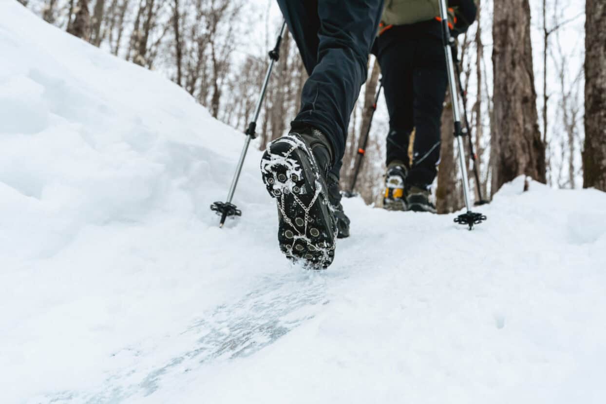 Hikers using ice cleats and crampons on a snow-covered trail